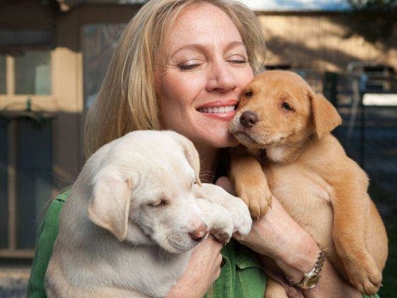 Laurie Hood of Alaqua Animal Refuge cuddles with two puppies.