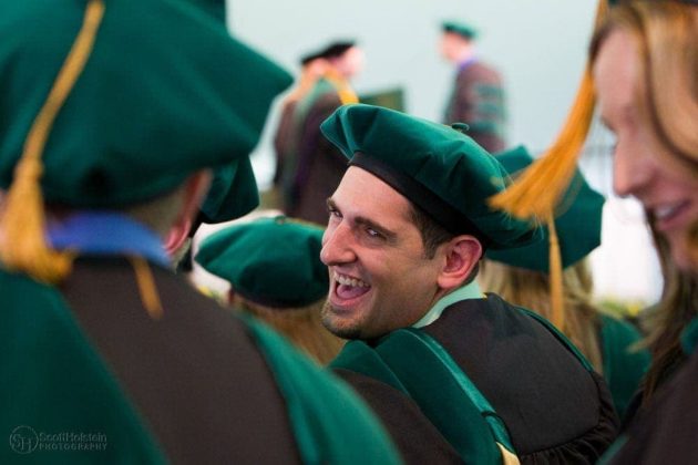 Higher education photography for a medical school: A medical student laughs during his graduation ceremony.