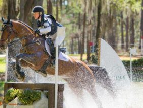 Water splashes as a horse and rider jump over a fence in a water feature during the Red Hills International Horse Trials.