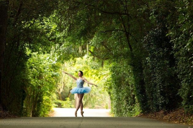 Small business photography for a dance studio: A ballerina in a tutu poses en pointe on a canopy road.